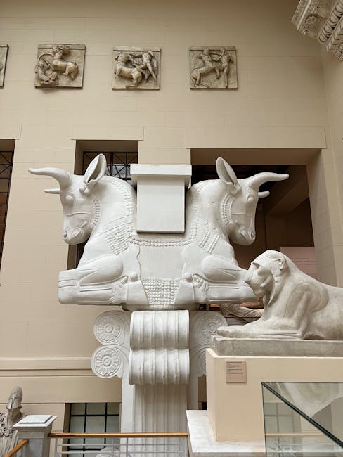 Inside a museum or gallery space with wooden display cabinets exhibiting ancient artifacts and sculptures, illuminated by natural light streaming through large windows, casting shadows on the white walls. The display cases are arranged in a row along the wall, with shelving inside holding various objects such as ceramic vases, small figurines, and papyrus scrolls. In the foreground, a black metal railing separates the display area from the viewer, suggesting a protective barrier for the exhibits. This setting reflects a typical environment for housing historical collections, relevant to house removals and relocation services like those offered by Man with Van Bloomsbury, who specialise in careful packing and furniture transport during home or museum moves. The scene captures the process of safeguarding delicate items, indicative of packing and moving logistics involved in professional removals near culturally significant locations like the British Museum.